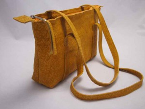 Camille in saffraangeel, is een vrouwelijke schoudertas, elegant en modern door de getunnelde handvaten.